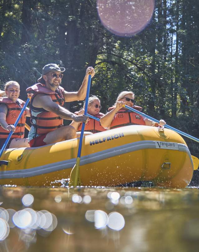 A group of people paddle on a white water raft on the McKenzie River