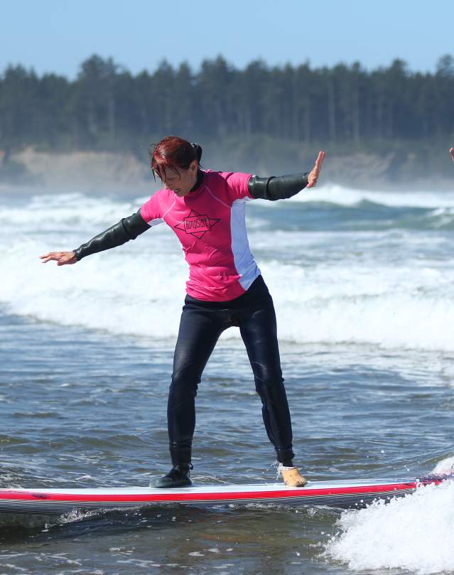 A person with limb loss surfs on the oregon coast