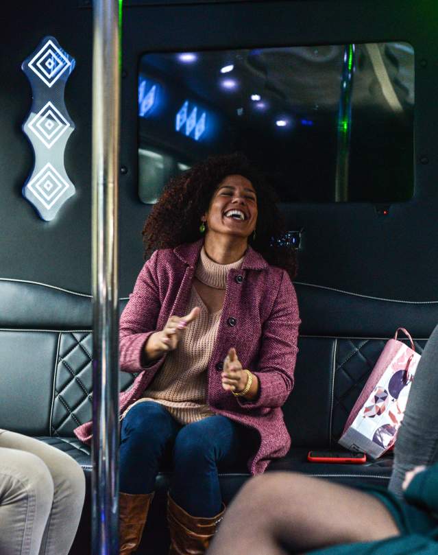 Woman laughing and clapping in a party bus.