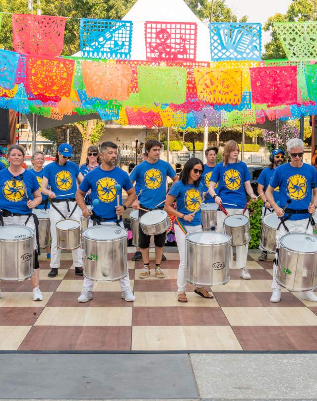 Band with drums performs outdoors.
