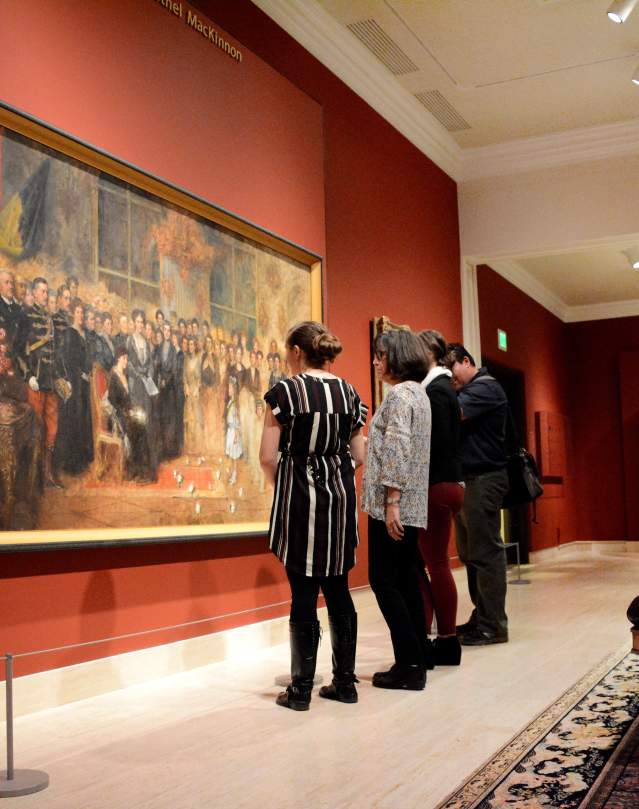 Four people stand in front of a large painting