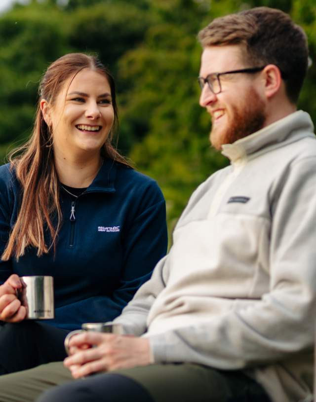 A couple enjoying a flask of hot drinks, sat on a bench taking a break from walking in the Yorkshire Wolds.