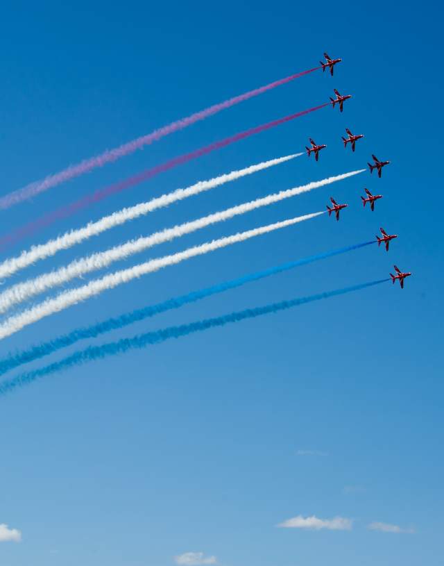 Red arrows flying in formation with coloured trails