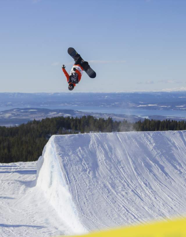 En snowboarder hopper høyt og tar en backflip i Ringkollen Alpintpark