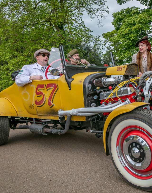 People dressed in 1940s clothes sat in retro car.