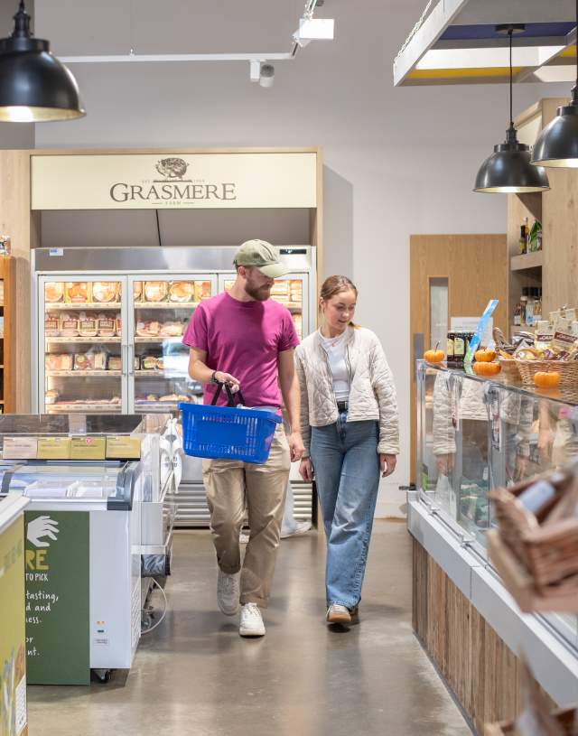 two people in farm shop with basket in hand surrounded by local produce