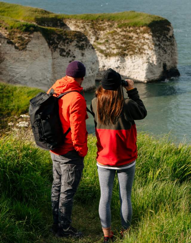 A couple using binoculars to look out to sea from flamborough head cliffs.