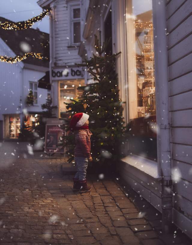 Barn ser i butikkvindu i juledekorert gate