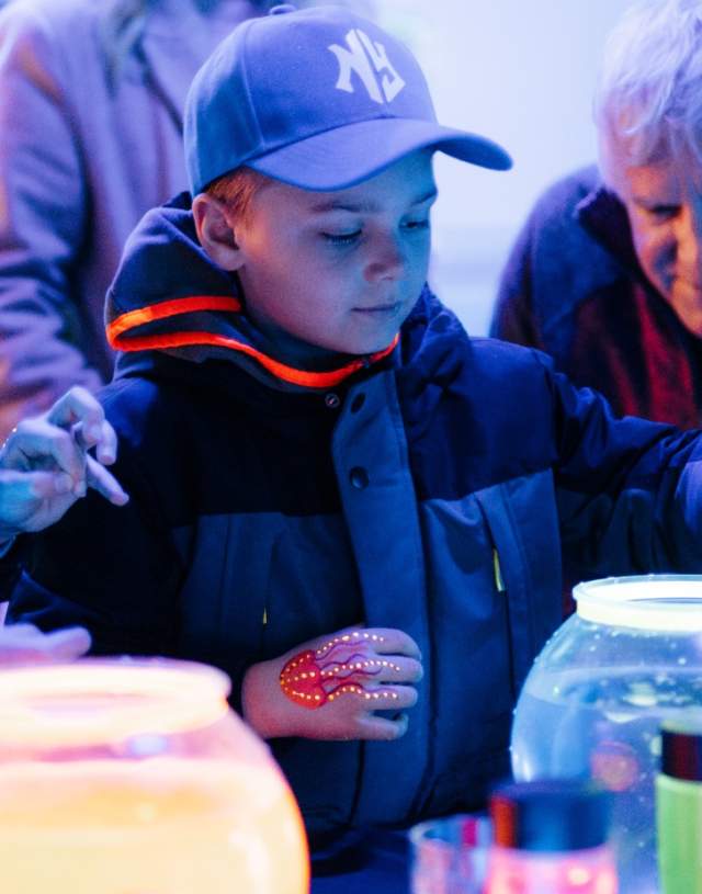 An old man and his grandchild mix chemicals in a neon bowl.