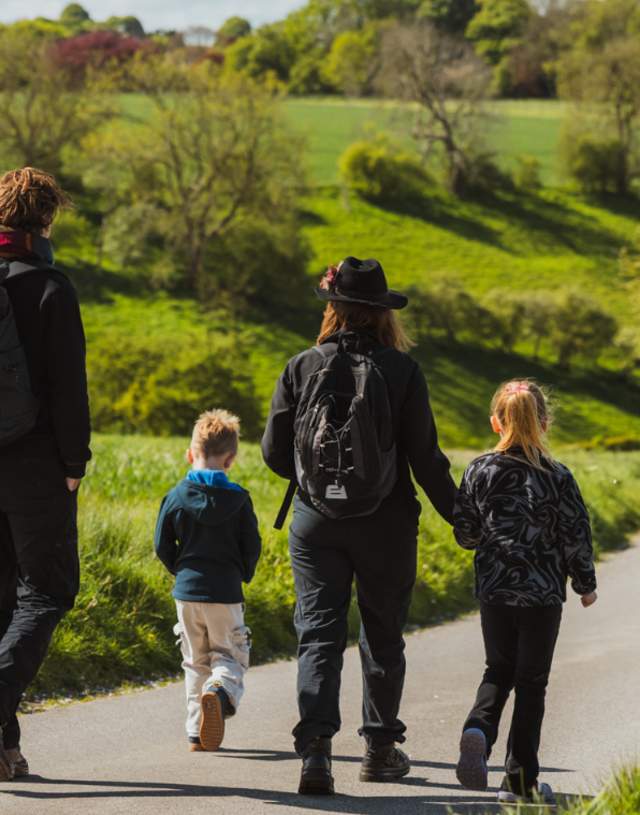 A family walking away from the camera down a single track path, surrounded by green fields in the Yorkshire Wolds.