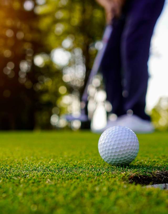 Golf ball in front of a putting hole on the golf course