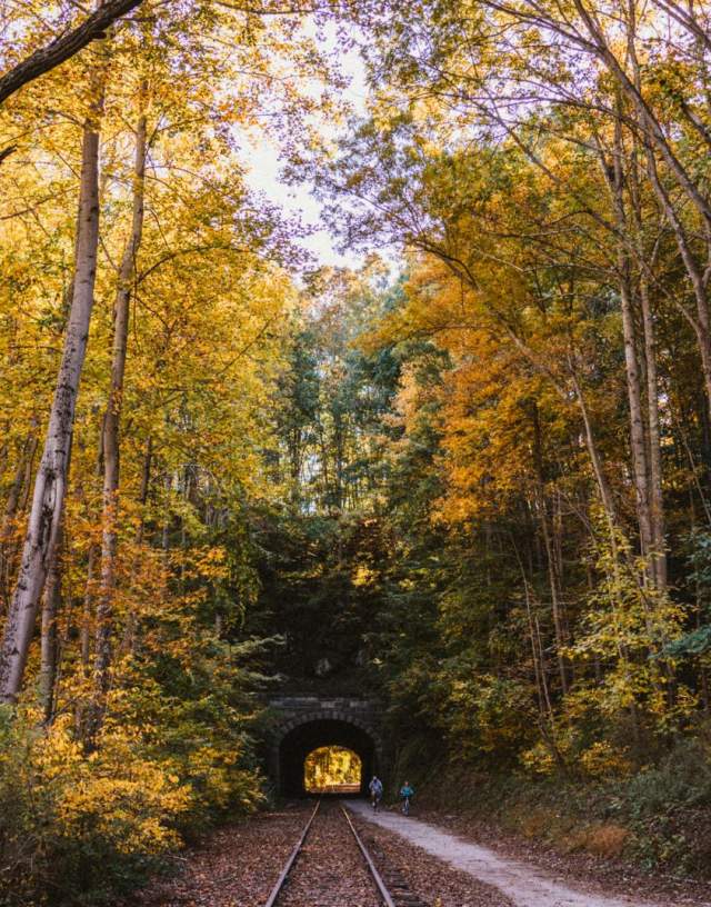 A couple bikes through the historic Howard Tunnel on the rail trail during autumn