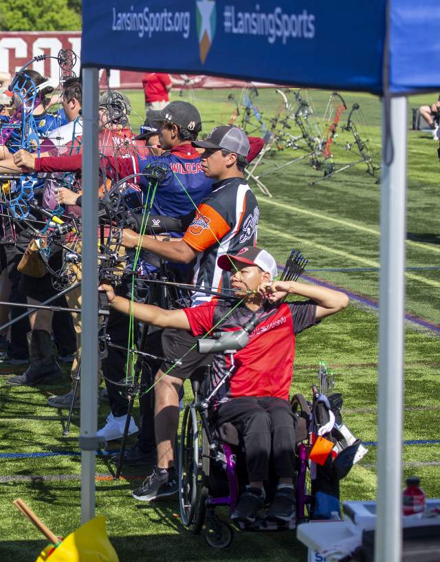 A group of archers line up and aim at the targets.
