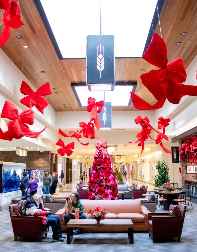 Festive holiday décor with large red bows and a Christmas tree inside West Acres Mall in Fargo, ND during winter shopping season.