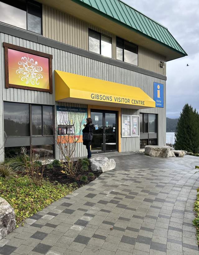 Exterior image of the Gibsons Visitor Centre, which includes a wide, paved accessible pathway, map and artwork