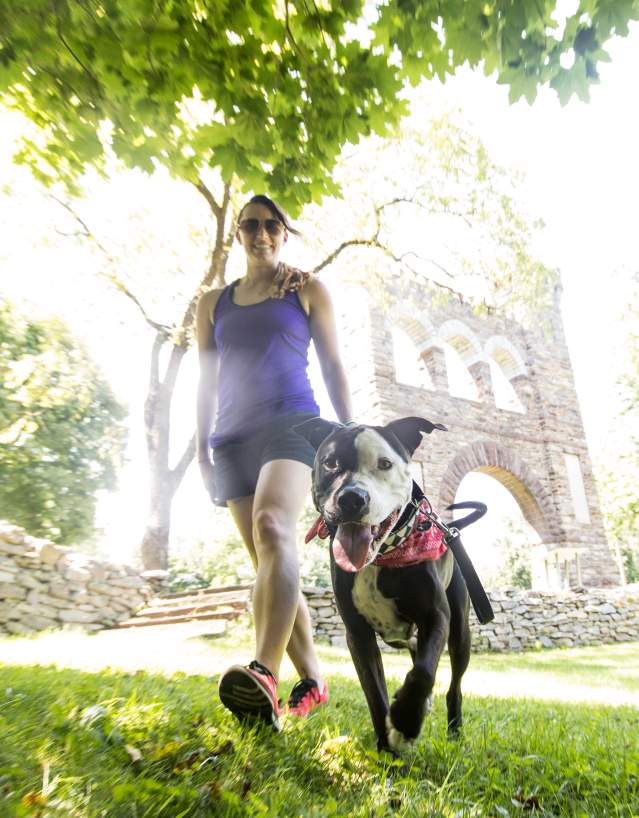 A woman and her dog hiking along the Appalachian Trail passing the War Correspondents Memorial Arch