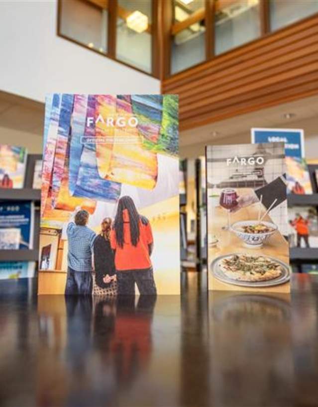 The Visitor Guide and Dining Guide standing upright on a tabletop in teh FM Visitors Center.