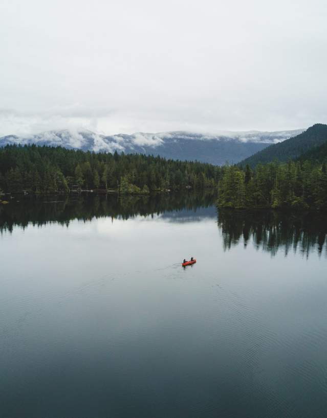 Aerial view of two people paddling a canoe across the lake.