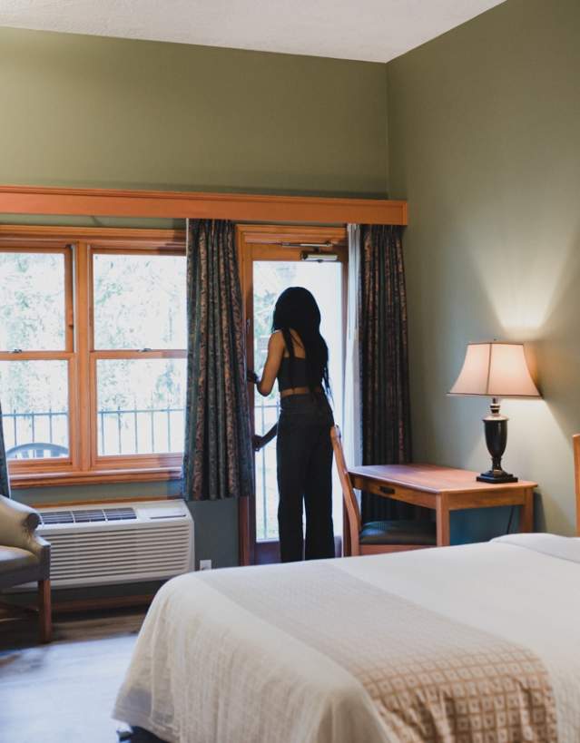 A person looking out their window in a hotel room.