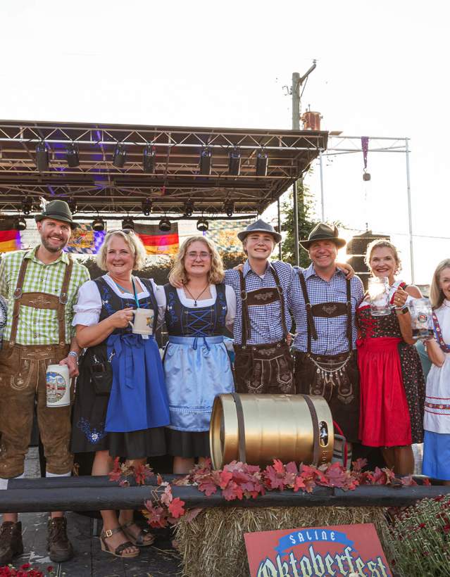 Row of people in German garb smiling for the camera at Saline Oktoberfest