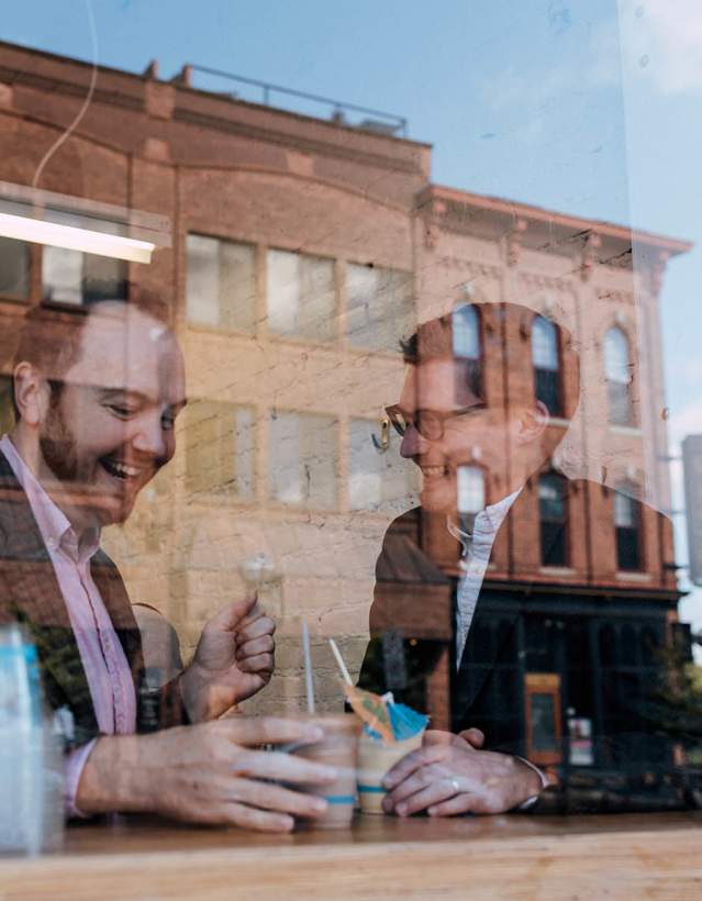Two men eating behind window at Frita Batidos