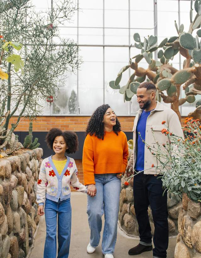 Two adults and one child walking through botanical gardens