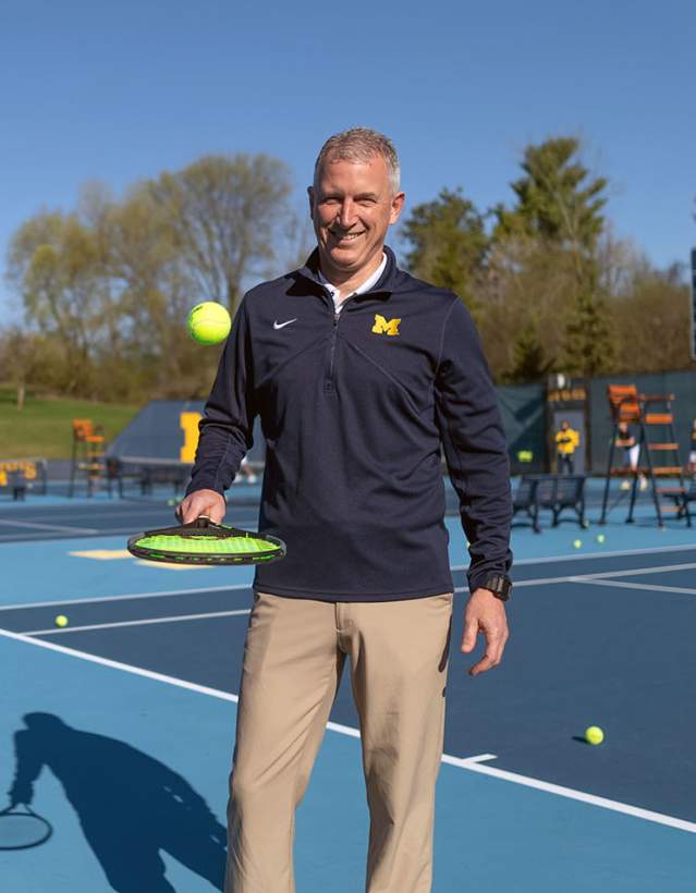 Man bouncing tennis ball with racket- U-M South Complex