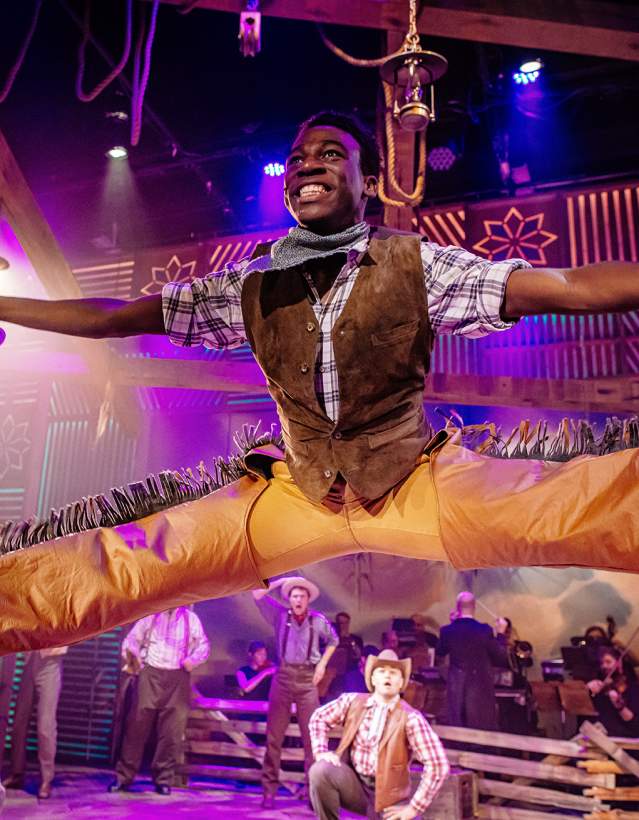 Man doing splits in the air, wearing country gear