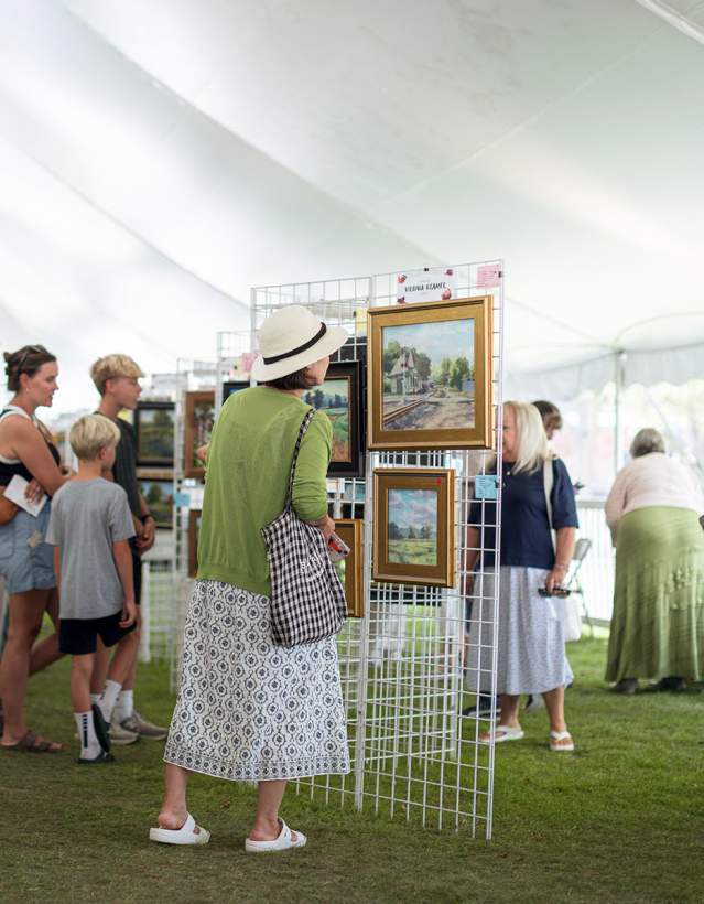 People looking at art in a tent during Paint Dexter Plain Aire