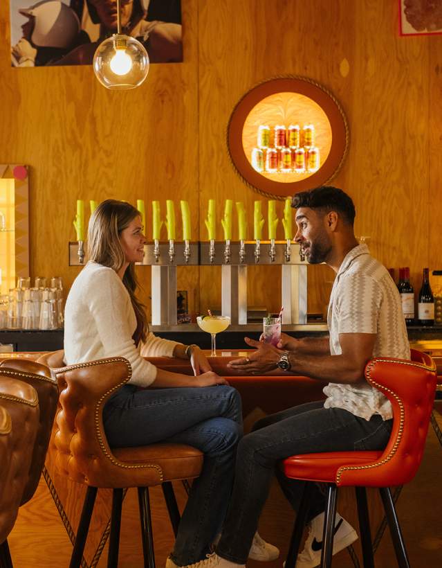Couple sitting at bar with beer taps behind them