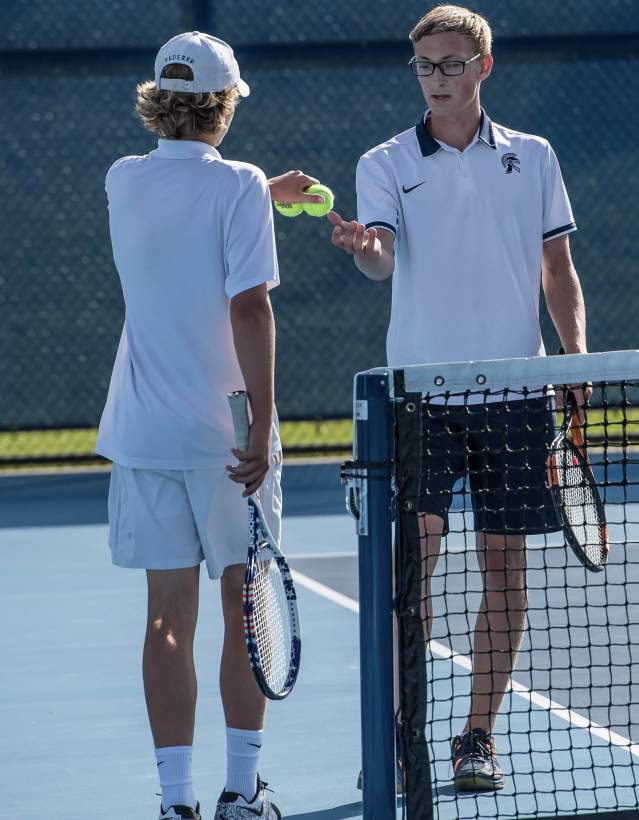 Two boys exchanging tennis balls on tennis court