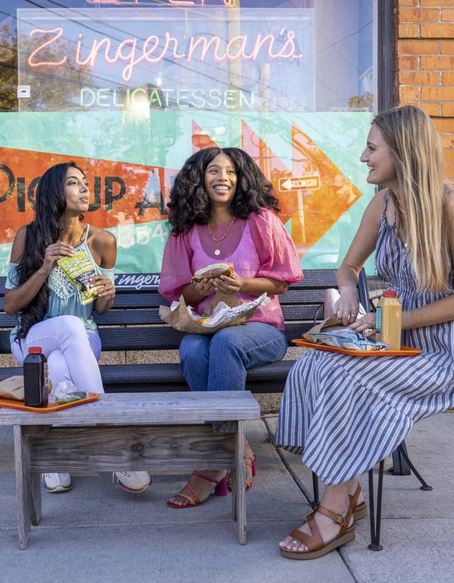 3 women eating out in front of Zingerman's Deli
