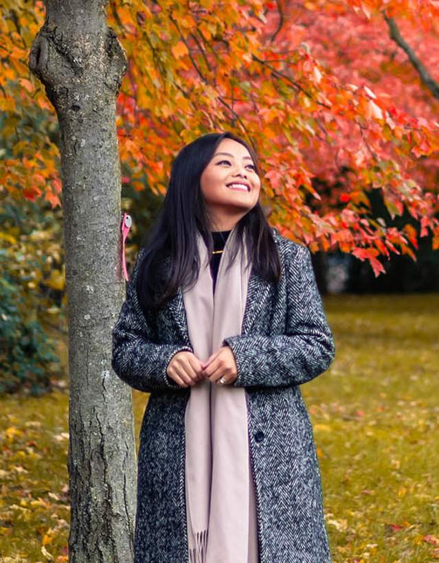Woman in coat and scarf walking in a fall scene