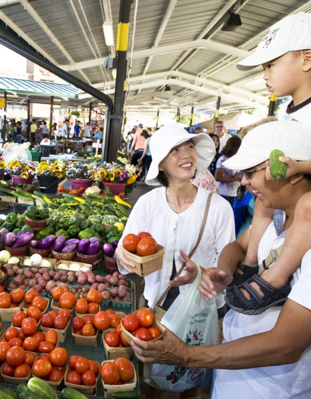 Family buying produce from a woman st the Ann Arbor Farmers Market