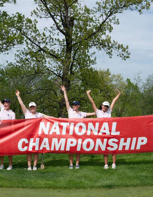 Group of women's golfers in front of NAIA National Championship banner