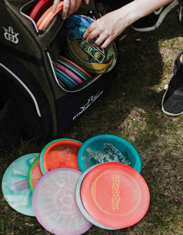 Person unpacking colorful disc golf frisbees from a bag