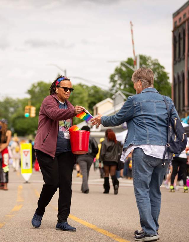 Woman handing out rainbow flags at Ypsi Pride