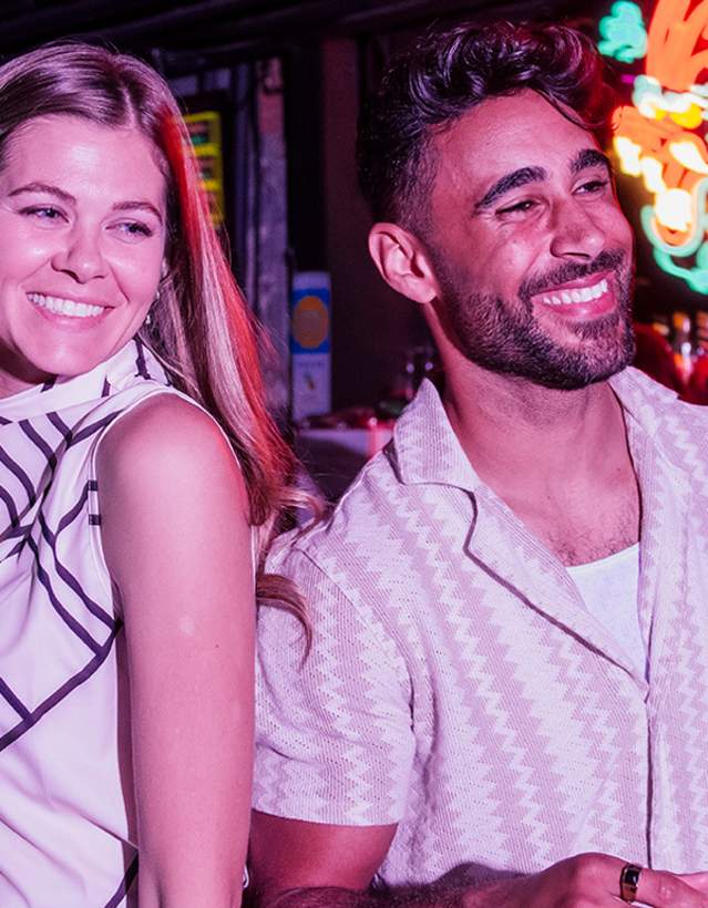 Couple having drinks at Lo-Fi with neon sign behind