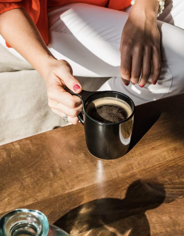 Person holding cup of coffee on a wooden table