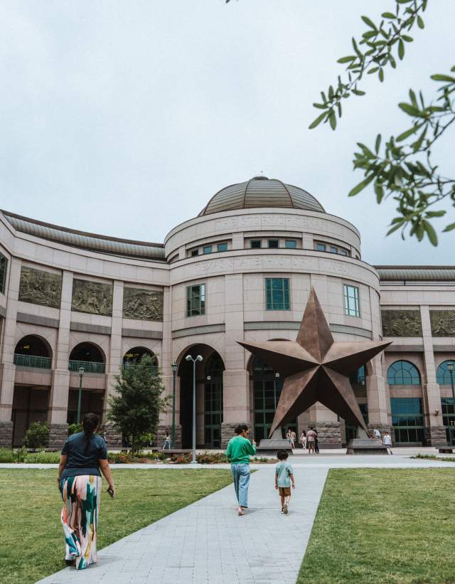 Two adults and a small child walking into the Bullock State History Museum.