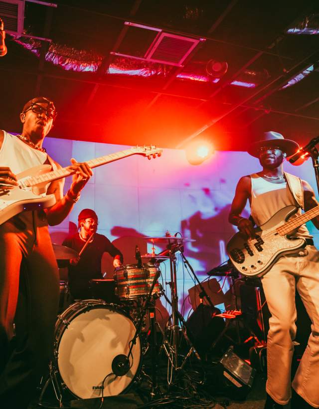 Band on stage with bright, colorful lights shining on them.