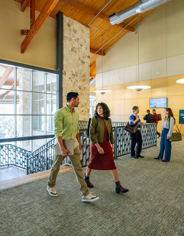 Image of a group of people dressed in business casual walking into the Palmer Events Center and chatting with one another.