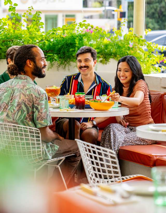 Image of a group of men and women sitting at a table smiling at one another on the patio at Joann's.