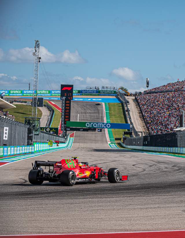 Two formula one cars round the turn in front of fan stands at Austins Circuit of The Americas racetrack
