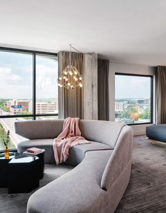 Large, modern hotel room with floor to ceiling windows overlooking Congress Avenue Bridge.