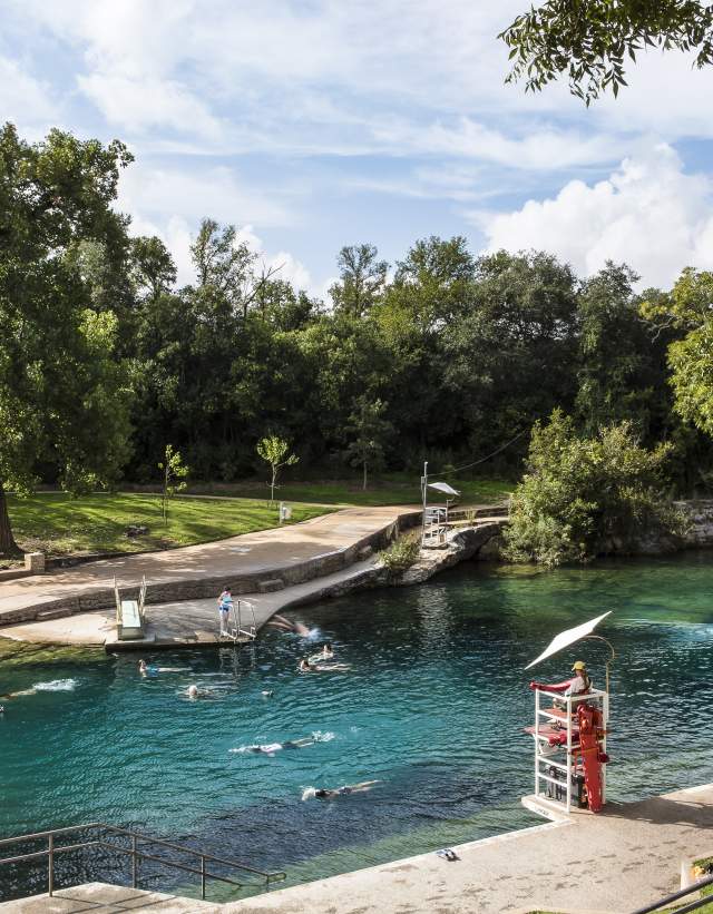 People swimming in Barton Springs Pool with lifeguard in stand