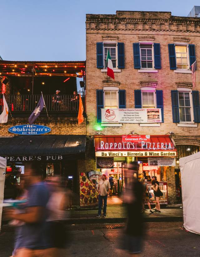 people walking down 6th Street in front of Roppolo's Pizzeria and Shakespeare's Pub in Austin Texas