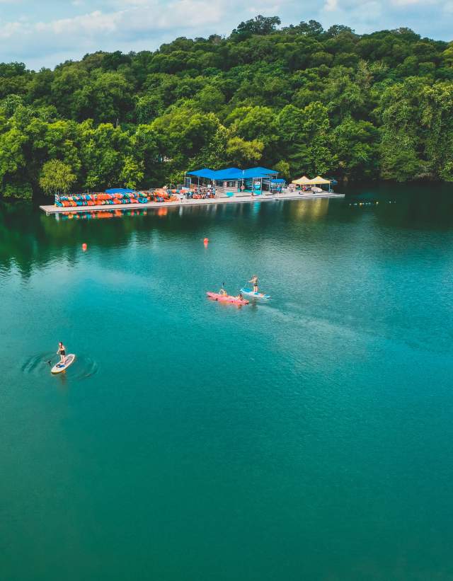 Aerial photo of people using kayak and paddle board rentals from Rowing Dock's shop on the shoreline of Lady Bird Lake Rowing Dock in Austin Texas