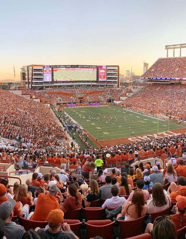Fans in burnt orange, white and grey filling the seats at DKR Stadium at the University of Texas at Austin.