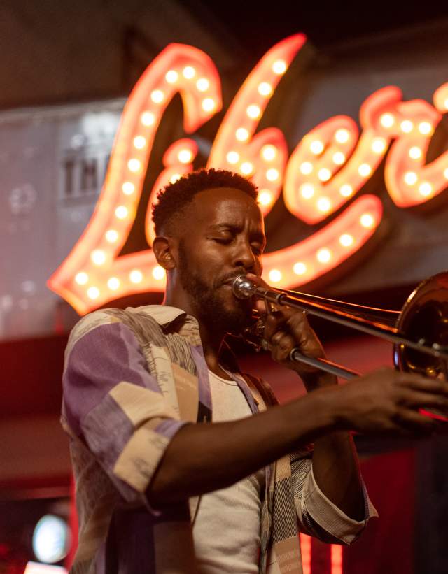 Austin musician Daniel Fears plays the trombone in front of The Liberty bar's lighted sign